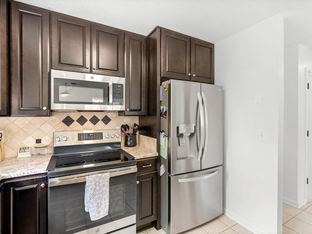 kitchen featuring light tile patterned floors, dark brown cabinets, appliances with stainless steel finishes, and tasteful backsplash