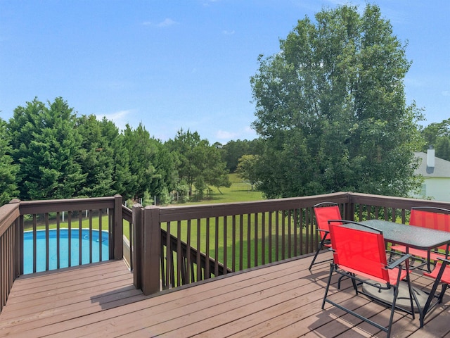 deck featuring outdoor dining space, an outdoor pool, and a yard