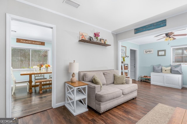 living room featuring visible vents, ornamental molding, dark wood-type flooring, ceiling fan, and baseboards