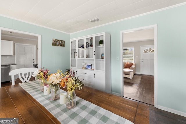 dining room with ornamental molding, dark wood-type flooring, visible vents, and baseboards