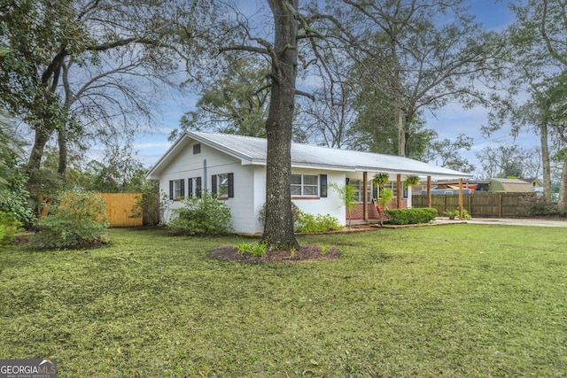 ranch-style house featuring metal roof, fence, and a front lawn