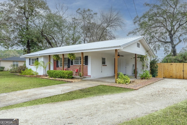 view of front of house featuring brick siding, fence, a ceiling fan, driveway, and a front yard