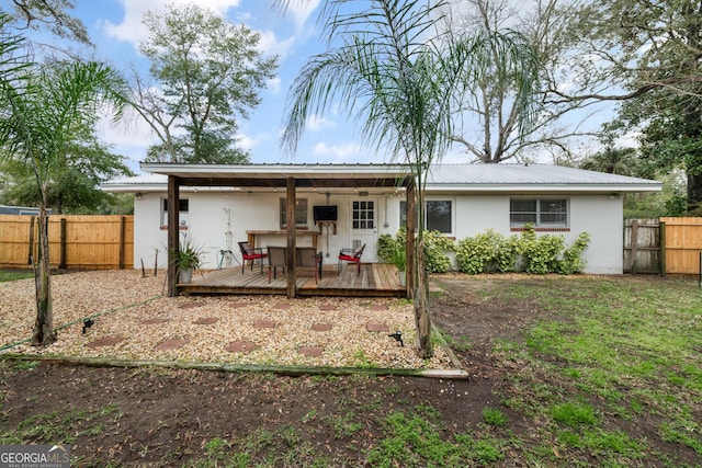 rear view of house featuring a deck, metal roof, a fenced backyard, and stucco siding