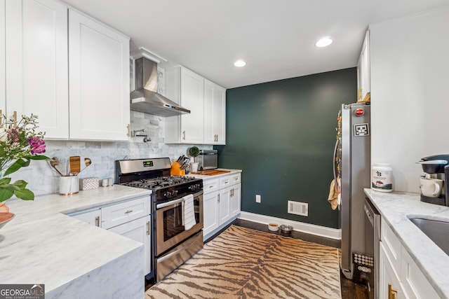 kitchen featuring stainless steel appliances, visible vents, white cabinets, wall chimney range hood, and tasteful backsplash