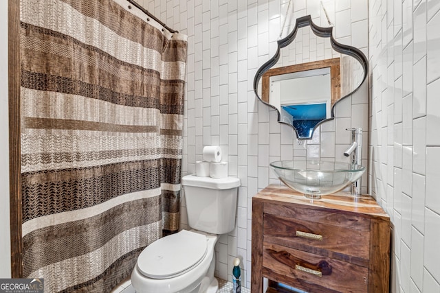 full bath with toilet, curtained shower, vanity, and tile walls