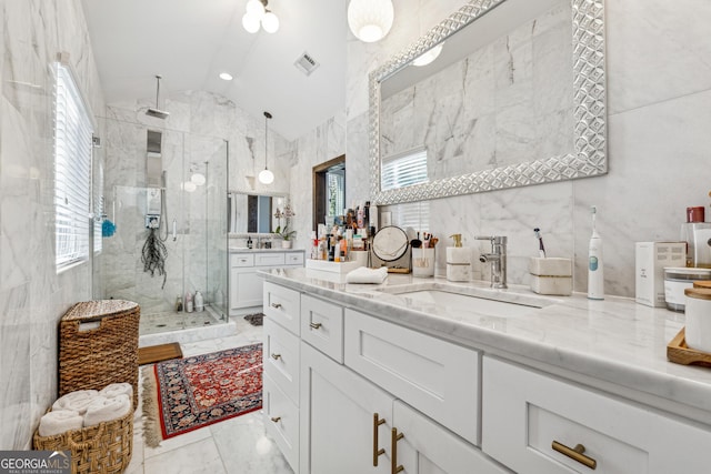 full bath with a marble finish shower, vaulted ceiling, tile walls, and vanity