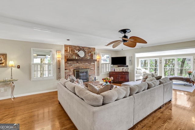 living room with a brick fireplace, wood finished floors, and a healthy amount of sunlight