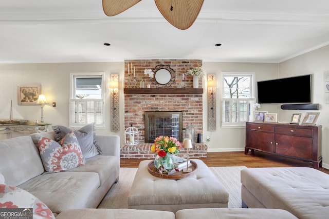 living area with a wealth of natural light, a brick fireplace, crown molding, and wood finished floors