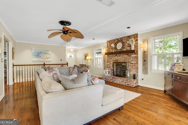 living area with baseboards, visible vents, a fireplace, ornamental molding, and light wood-type flooring