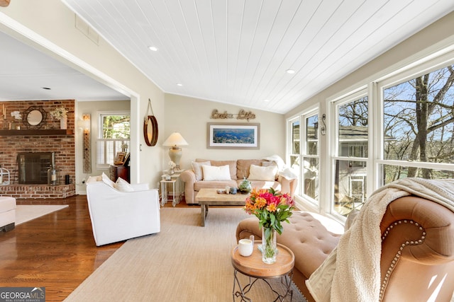 living area with a brick fireplace, wood ceiling, vaulted ceiling, recessed lighting, and wood finished floors