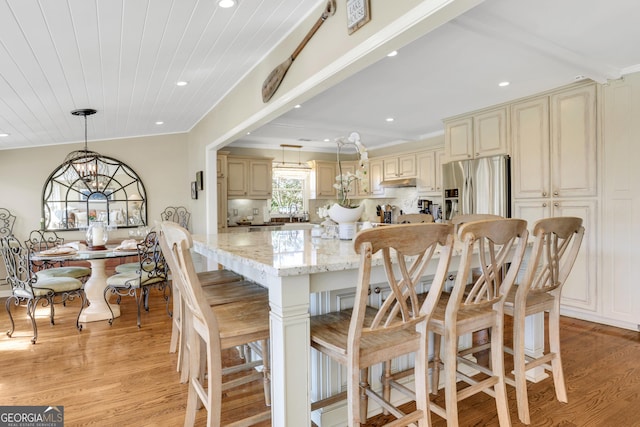 kitchen with a notable chandelier, light stone countertops, cream cabinets, and stainless steel fridge with ice dispenser