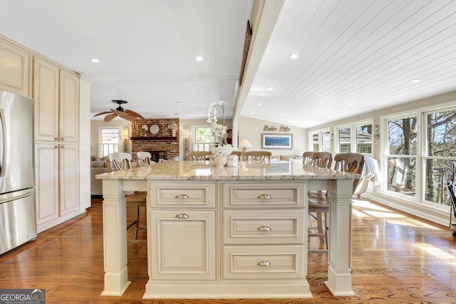 kitchen featuring a breakfast bar, cream cabinetry, open floor plan, and freestanding refrigerator