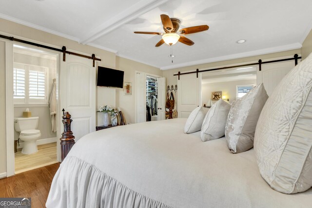 bedroom with a barn door, crown molding, and wood finished floors