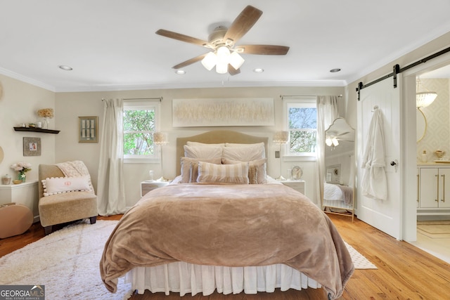 bedroom featuring recessed lighting, light wood-type flooring, a barn door, and ornamental molding