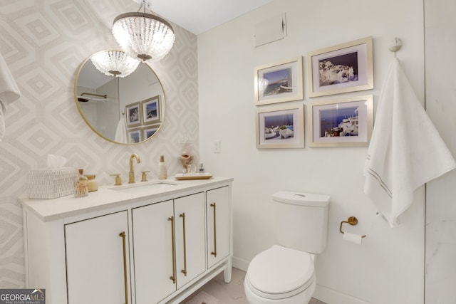 bathroom featuring vanity, baseboards, wallpapered walls, toilet, and a chandelier