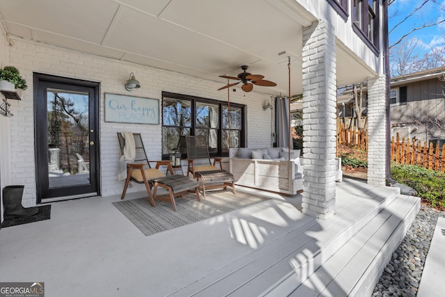 wooden terrace with an outdoor hangout area, a ceiling fan, and fence