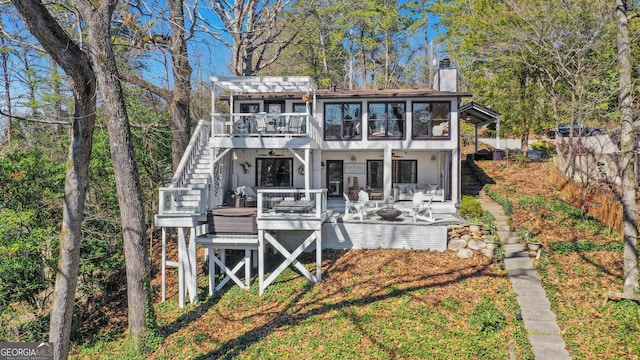 rear view of house featuring an outdoor living space with a fire pit, fence, stairs, a chimney, and a deck