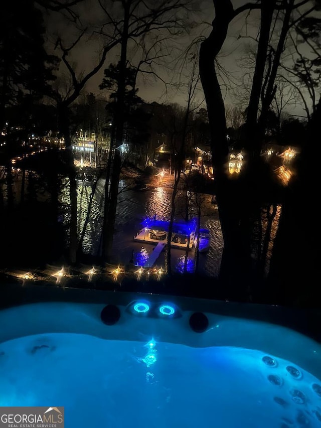 pool at twilight with an outdoor hot tub