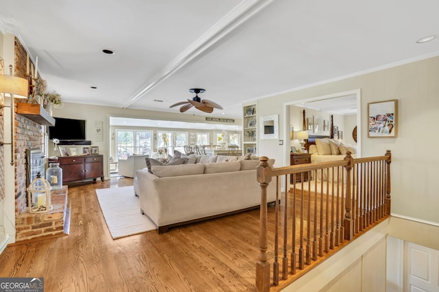 living area with a fireplace, crown molding, wood finished floors, and a ceiling fan