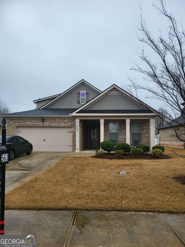 view of front of house featuring driveway, brick siding, an attached garage, and a front yard