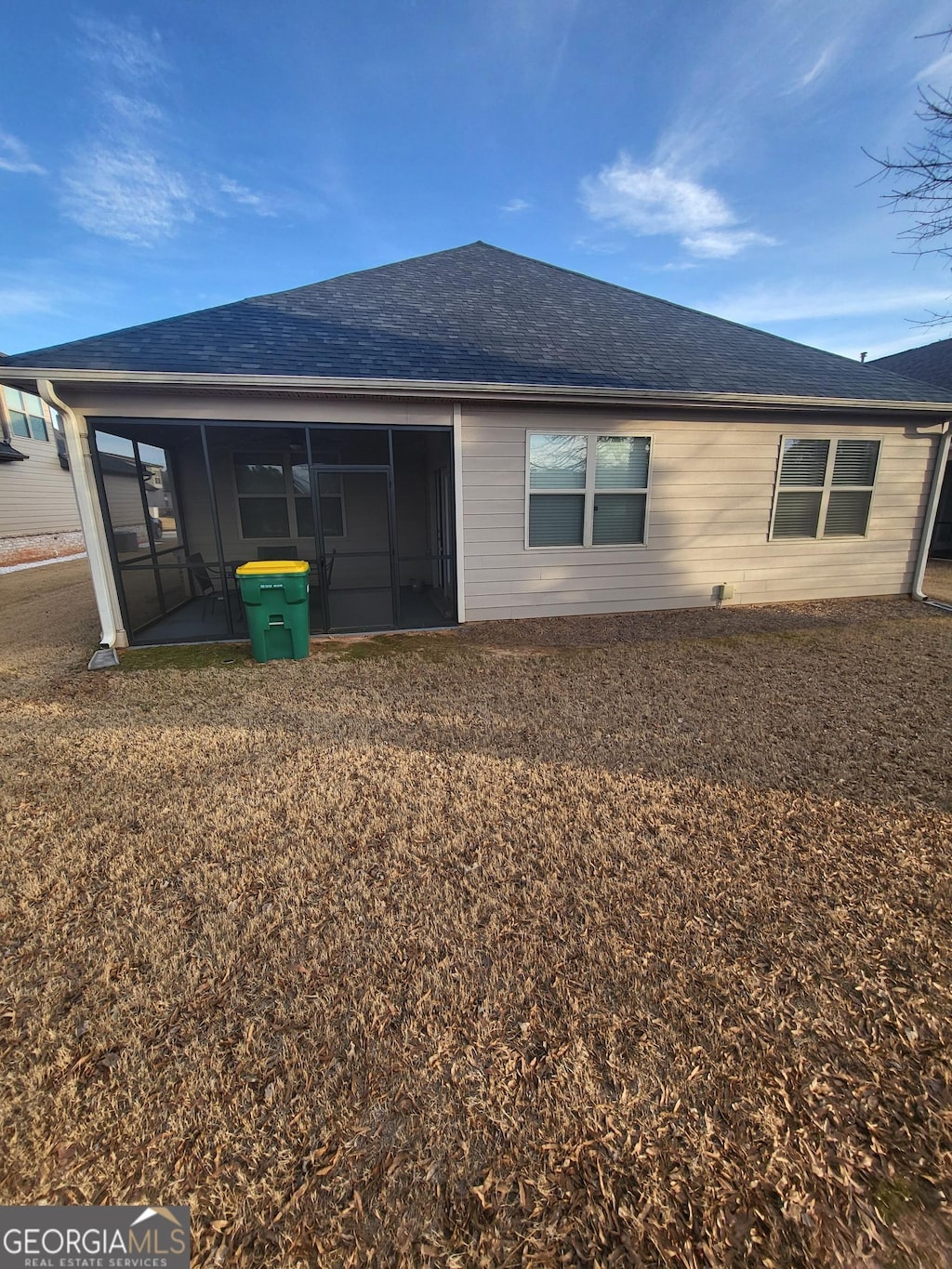 back of house featuring a yard, roof with shingles, and a sunroom