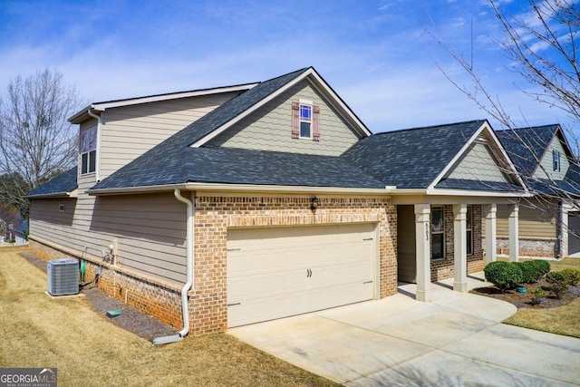 view of front of house with brick siding, central air condition unit, driveway, and roof with shingles