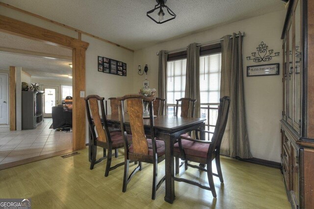 dining space featuring light wood-type flooring, visible vents, plenty of natural light, and a textured ceiling