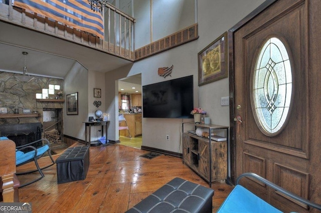 foyer with a towering ceiling, hardwood / wood-style flooring, plenty of natural light, and a fireplace