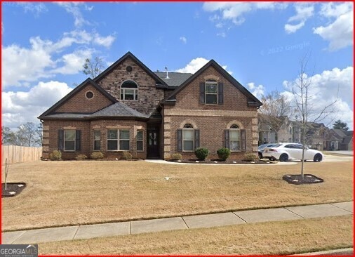 traditional-style home featuring brick siding, fence, and a front lawn