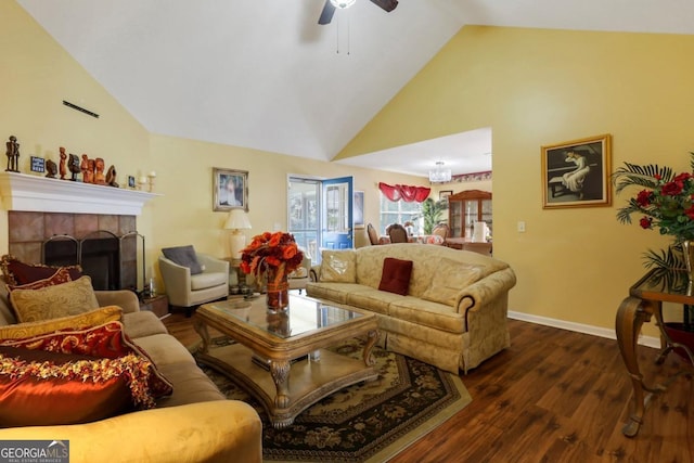 living area featuring baseboards, a ceiling fan, a tile fireplace, dark wood-style floors, and high vaulted ceiling