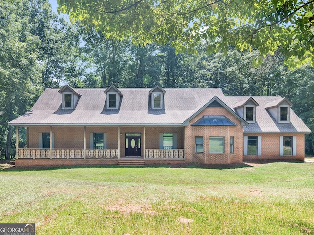 view of front of home featuring roof with shingles, brick siding, a porch, and a front yard