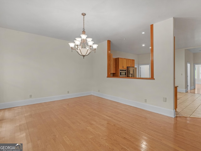 unfurnished living room with recessed lighting, light wood-style flooring, baseboards, and an inviting chandelier