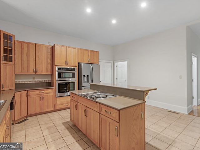 kitchen with stainless steel appliances, visible vents, glass insert cabinets, light tile patterned flooring, and a kitchen island