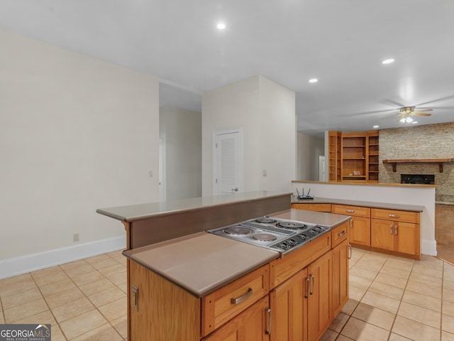 kitchen with light tile patterned floors, a kitchen island, a ceiling fan, and stainless steel electric stovetop