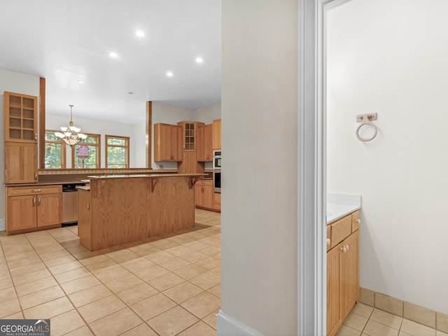 kitchen featuring glass insert cabinets, stainless steel appliances, a kitchen bar, a notable chandelier, and light tile patterned flooring