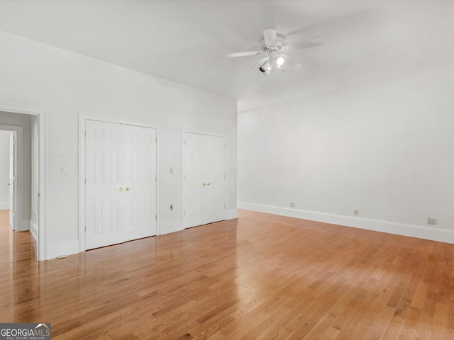 unfurnished bedroom with multiple closets, baseboards, and light wood finished floors