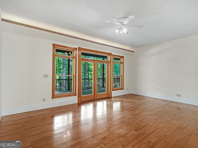 empty room with french doors, visible vents, baseboards, and wood finished floors