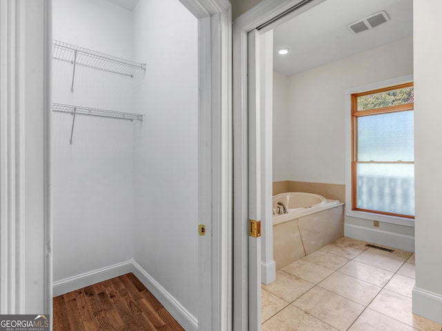 bathroom with a bath, baseboards, visible vents, and tile patterned floors