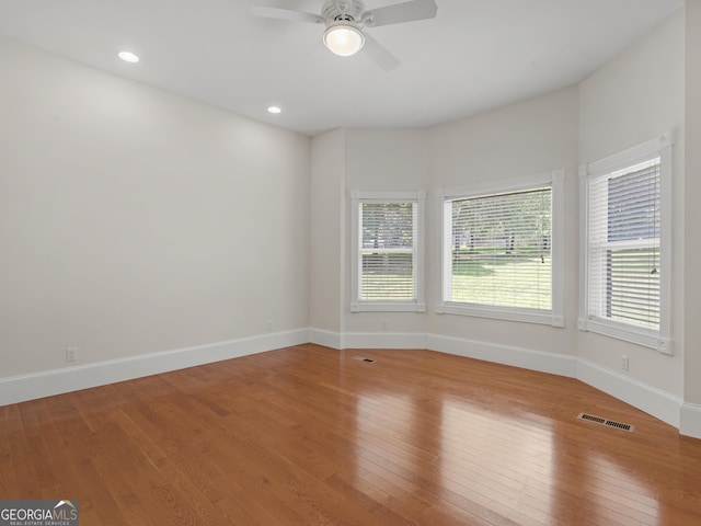 unfurnished room with baseboards, visible vents, and hardwood / wood-style floors