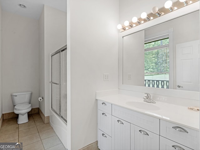 full bath featuring enclosed tub / shower combo, tile patterned flooring, toilet, vanity, and baseboards