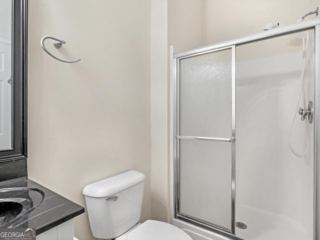 bathroom featuring a stall shower, vanity, and toilet