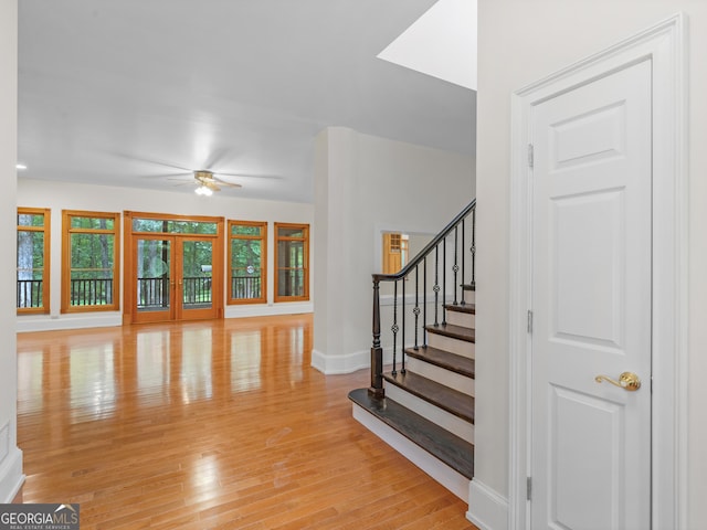 interior space with light wood finished floors, baseboards, ceiling fan, stairway, and french doors