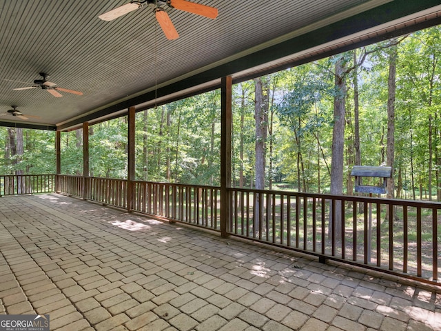 unfurnished sunroom featuring a ceiling fan and a view of trees