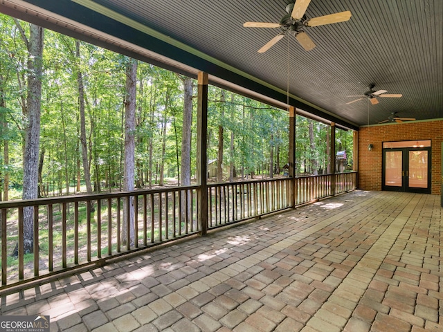 unfurnished sunroom featuring a forest view and ceiling fan