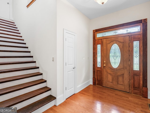 foyer featuring stairs, visible vents, light wood-style flooring, and baseboards