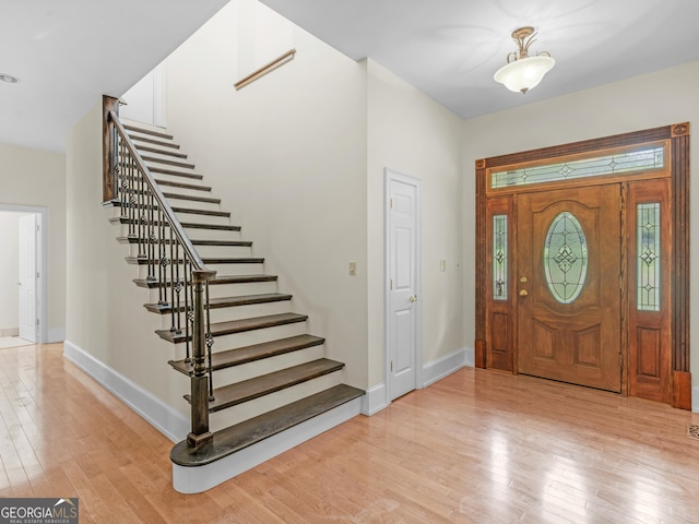 entryway with baseboards, stairway, and light wood finished floors