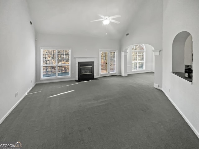 unfurnished living room with high vaulted ceiling, carpet, ceiling fan, and a fireplace with flush hearth