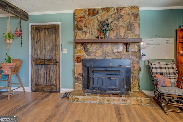 living area with a textured ceiling, baseboards, wood finished floors, and crown molding