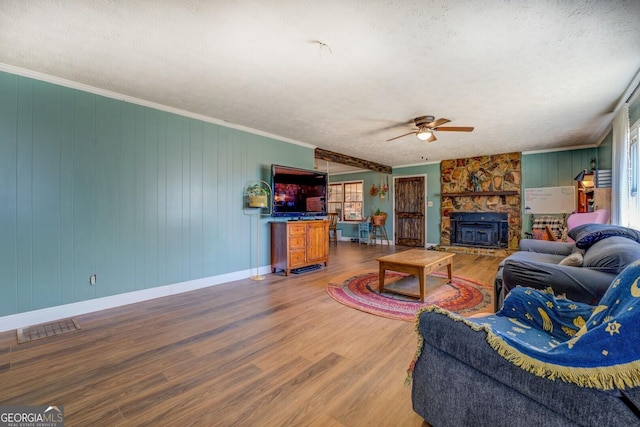 living room with a textured ceiling, ornamental molding, wood finished floors, and visible vents