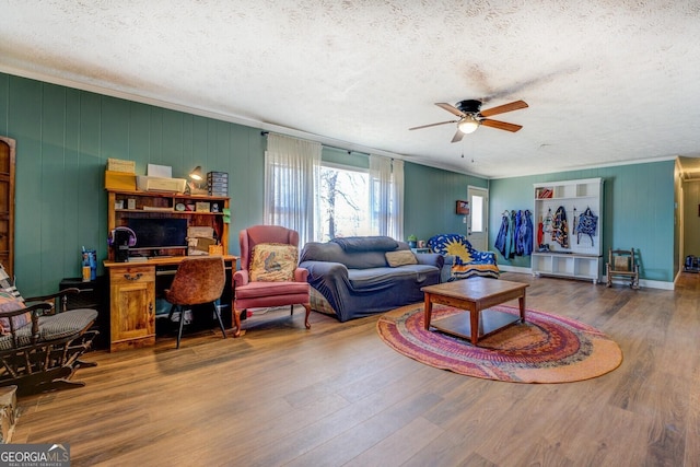 living room featuring a ceiling fan, crown molding, a textured ceiling, and wood finished floors